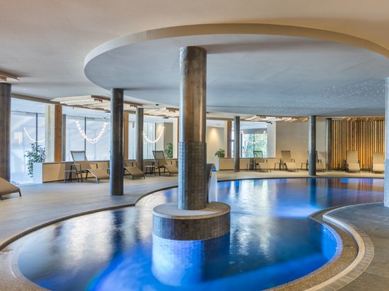 Das richtige Zimmer für Ihren Pragser-Wildsee-Urlaub Moderner Innenpool mit blau beleuchtetem Wasser und Liegestühlen