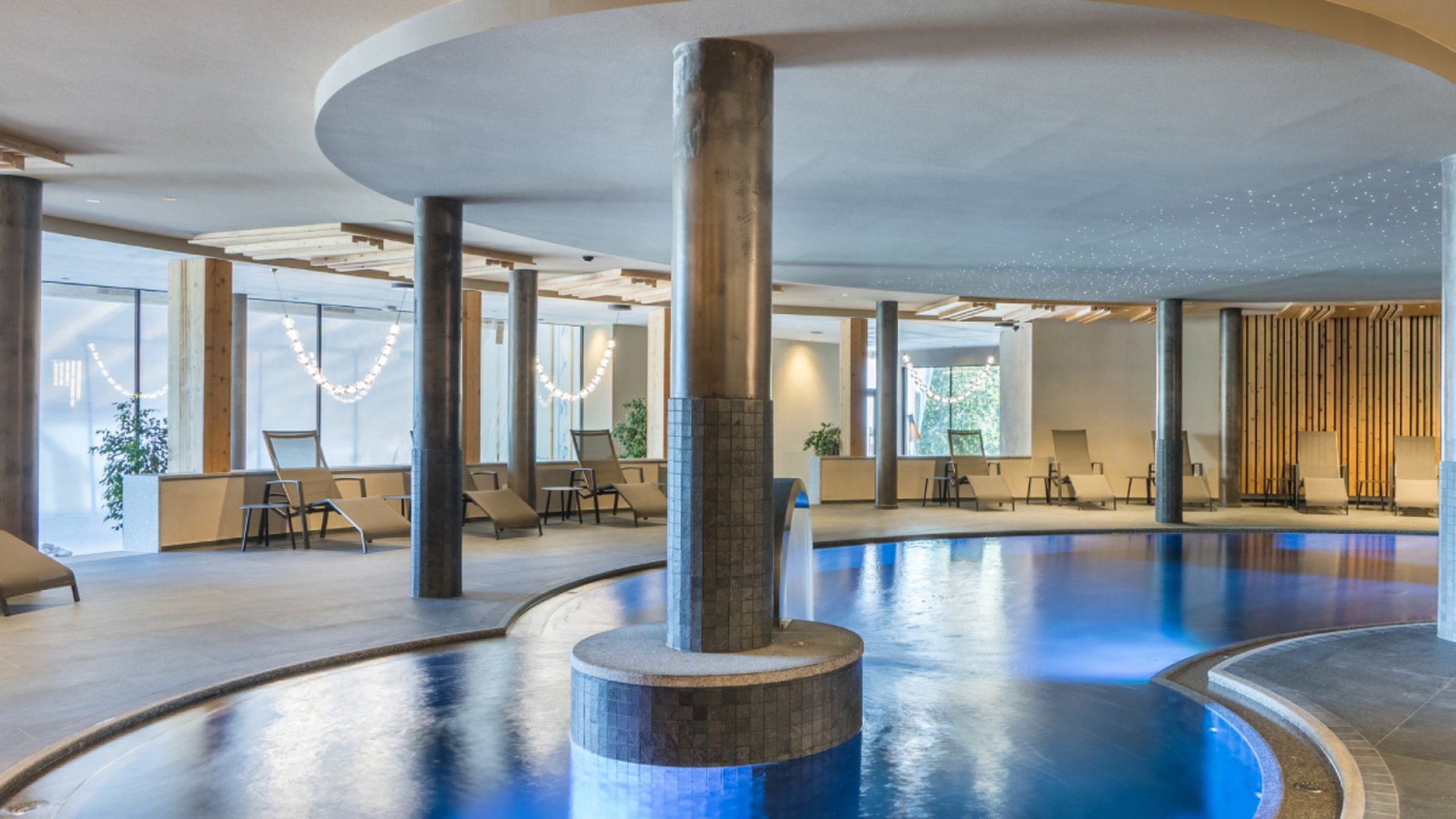 Concedetevi una pausa Piscina interna moderna con acqua illuminata di blu e lettini