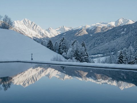 Le novità del nostro hotel a 4 stelle tra le Dolomiti Montagne innevate riflesse in un lago calmo sotto un cielo azzurro