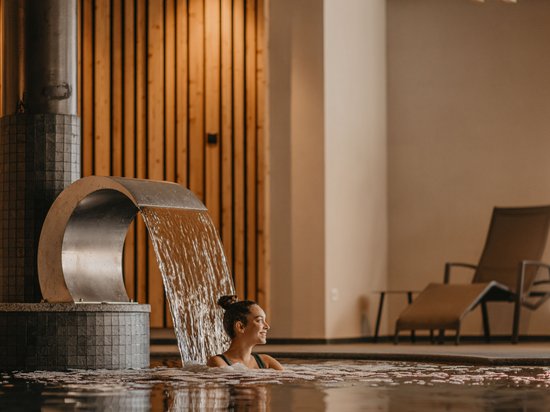 4-Sterne-Hotel am Kronplatz: Ihr perfektes Urlaubszuhause Frau entspannt im Hallenbad unter Wasserfall