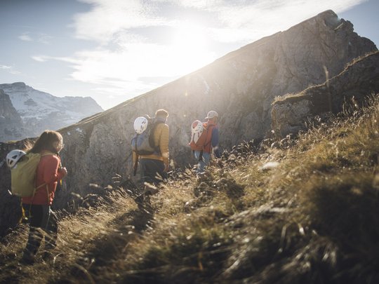 Novità dal nostro hotel al Plan de Corones Tre escursionisti con caschi su un sentiero montano soleggiato