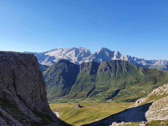 Neuigkeiten unseres Hotels nahe dem Pragser Wildsee Berglandschaft mit schneebedeckten Gipfeln und kurviger Straße bei klarem Himmel