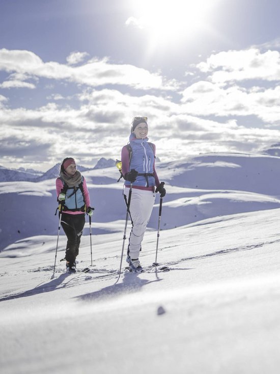 Der Kronplatz aus nächster Nähe: Ihr Aktivhotel in Südtirol Zwei Frauen beim Skifahren auf schneebedecktem Berg bei sonnigem Wetter