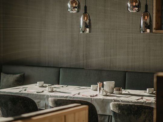 Le novità del nostro hotel a 4 stelle tra le Dolomiti Sala da pranzo moderna con tavolo apparecchiato e lampade a sospensione