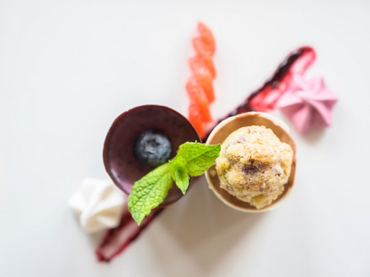 Regionale, alpine Küche im Hotel am Kronplatz in Südtirol Gourmet-Dessert mit Minzblatt, Blaubeere und kleinen Meringue-Stücken