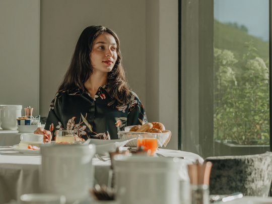 Concedetevi una pausa Donna seduta a tavola apparecchiata per colazione in stanza luminosa con finestra