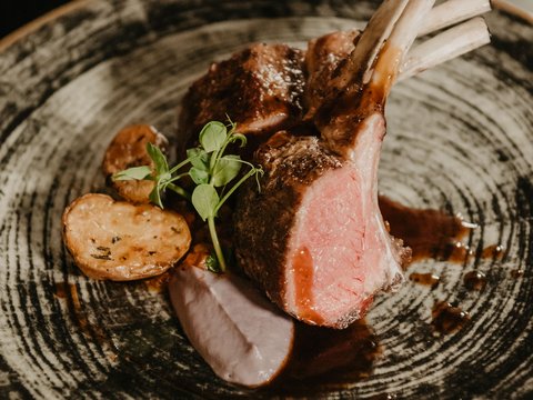 A swim in Lago di Braies? A hotel with a pool? Let’s go for a dip! Grilled lamb chops with potatoes and sauce on a decorative plate