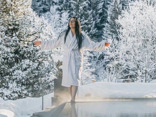 Hotel al Plan de Corones con spa: vacanza à la Christoph Donna in accappatoio vicino a piscina calda con bosco innevato sullo sfondo