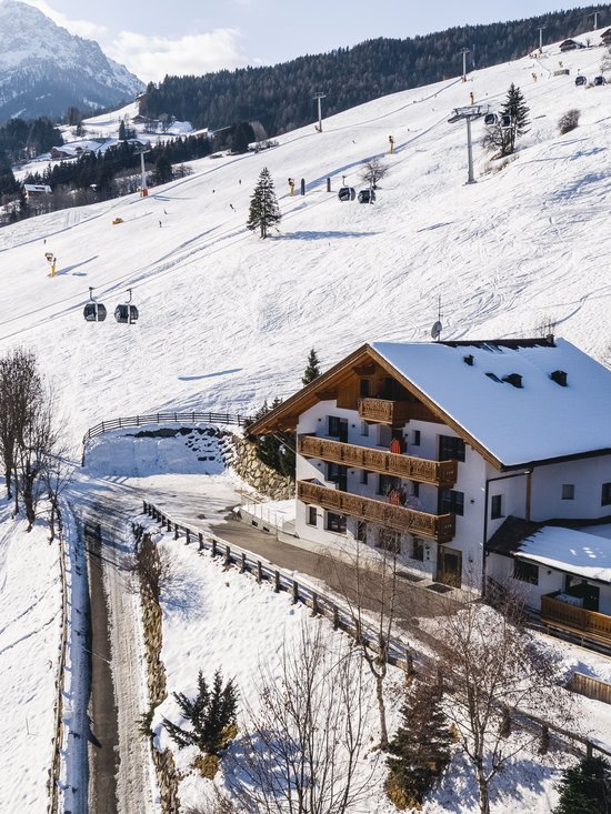 4-Sterne-Hotel am Kronplatz: Ihr perfektes Urlaubszuhause Skigebiet mit Sesselliften und schneebedecktem Haus in den Bergen