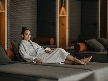 Le novità del nostro hotel a 4 stelle tra le Dolomiti Donna rilassata in accappatoio su divano lounge in ambiente moderno