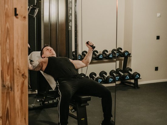 4-Sterne-Hotel am Kronplatz: Ihr perfektes Urlaubszuhause Mann trainiert mit Kabelzug in Fitnessstudio vor Spiegel