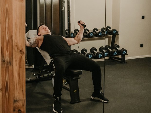 Fitness am Pragser Wildsee: Übernachtung im Hotel Christoph Mann trainiert mit Kabelzug in Fitnessstudio vor Spiegel