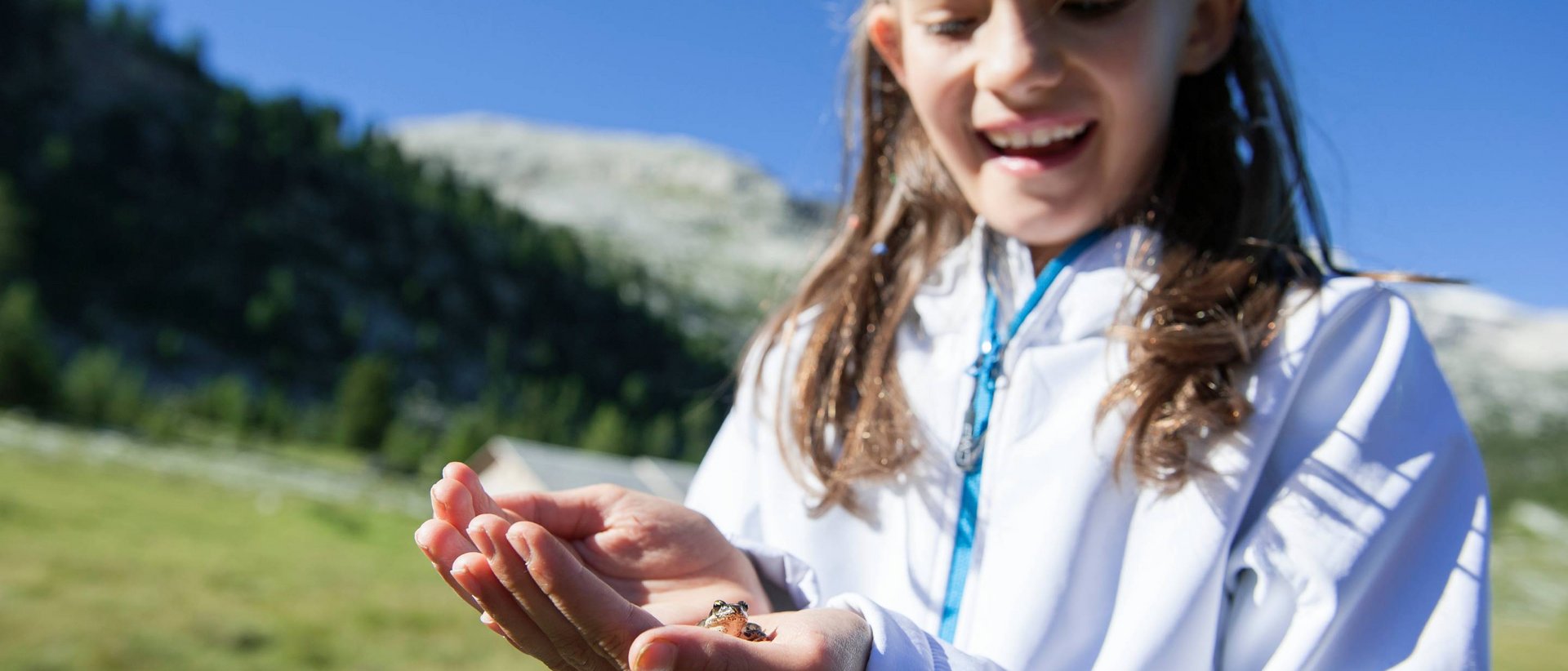 Tubing estivo Ragazza sorride tenendo una piccola rana nelle mani in natura