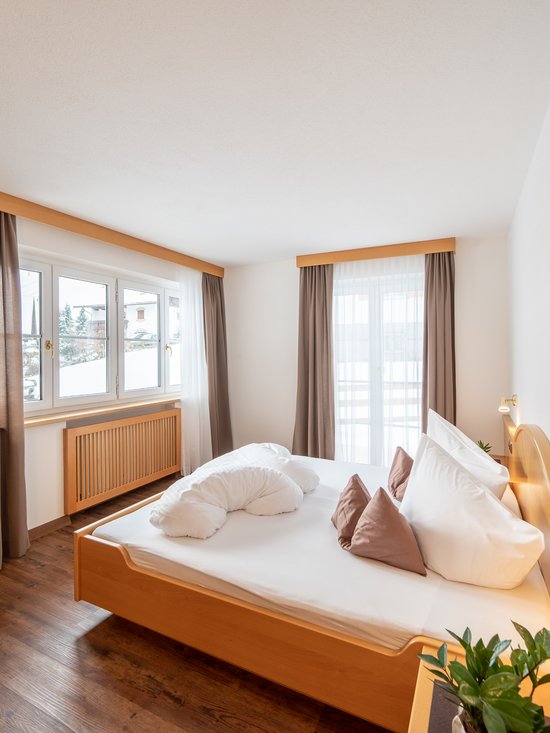 4-Sterne-Hotel am Kronplatz: Ihr perfektes Urlaubszuhause Hell eingerichtetes Hotelzimmer mit Bett, TV und Fenster mit Vorhängen