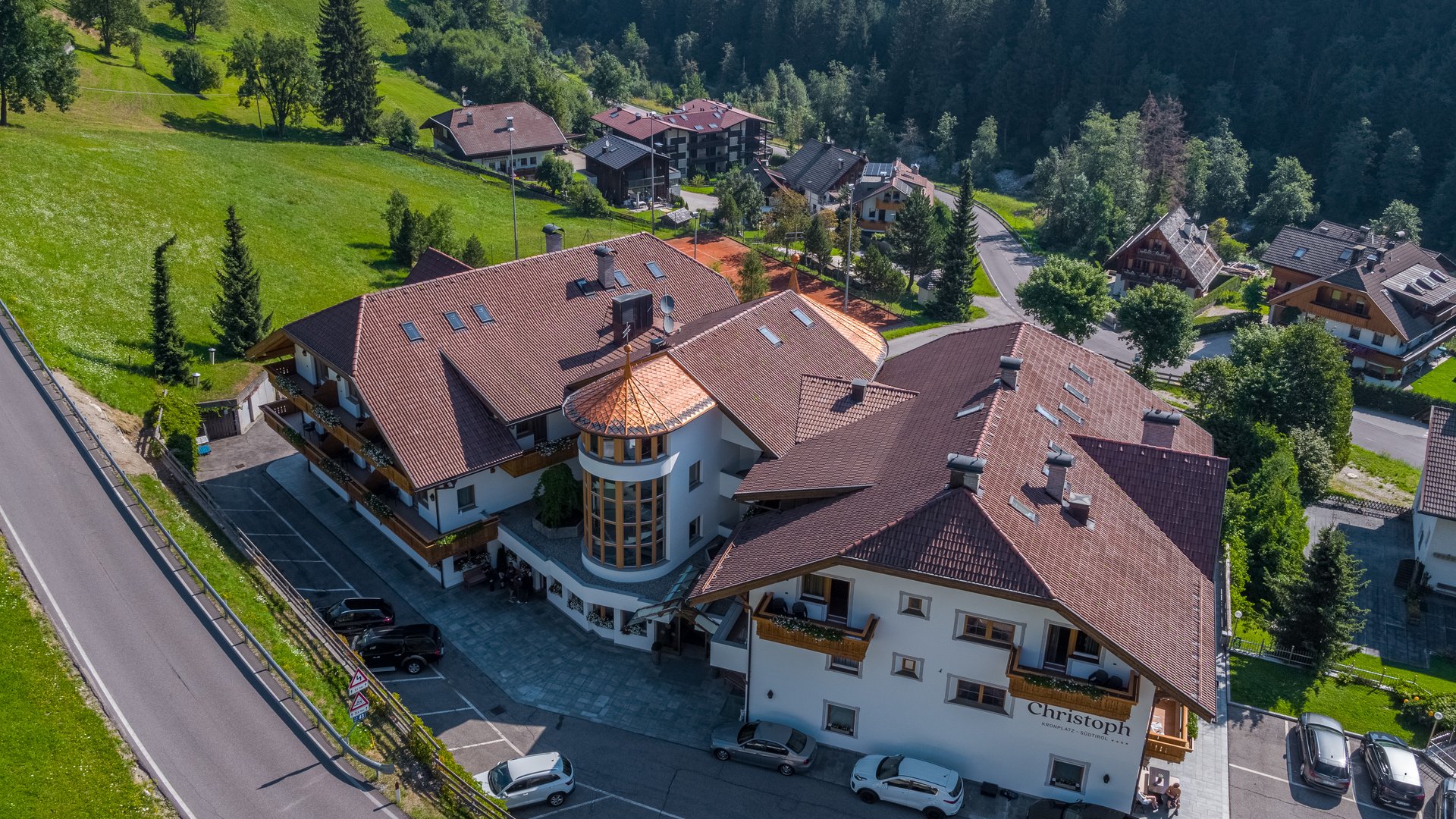 Willkommen in Olang: Hotel Christoph Hotel Christoph mit Bergkulisse und Wald in sonniger Landschaft
