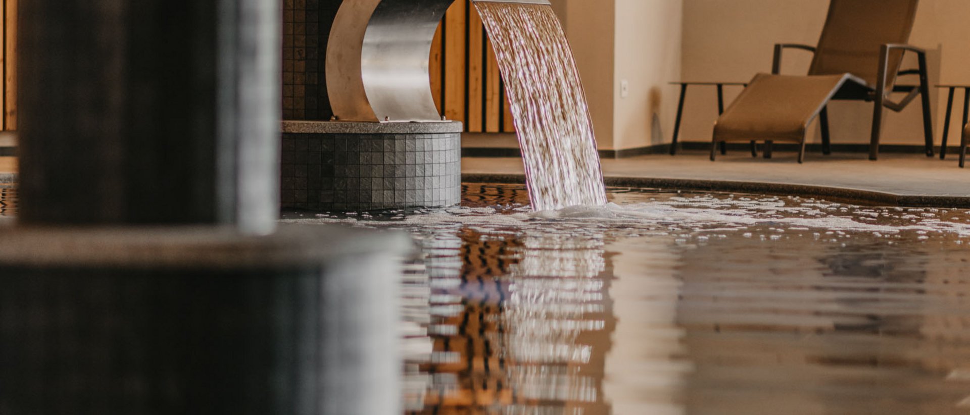 I benefici del wellness in inverno Piscina benessere moderna con cascata d'acqua e sedie a sdraio sullo sfondo