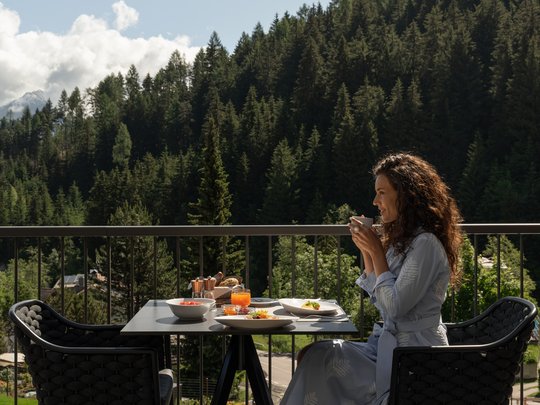 Gönnen Sie sich eine Auszeit Frau trinkt Kaffee auf Balkon mit Bergblick und Frühstückstisch