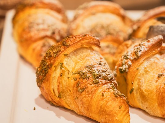 Regionale, alpine Küche im Hotel am Kronplatz in Südtirol Frische Croissants mit Kräutern auf weißem Teller