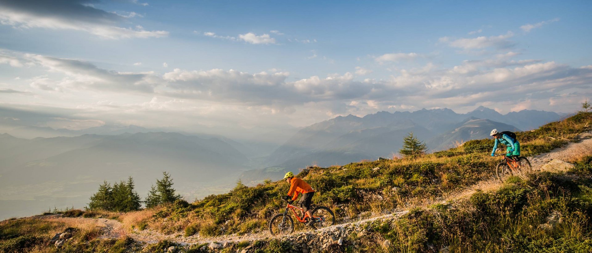 Radfahren im Herbst Zwei Mountainbiker fahren auf einem Bergweg bei Sonnenuntergang