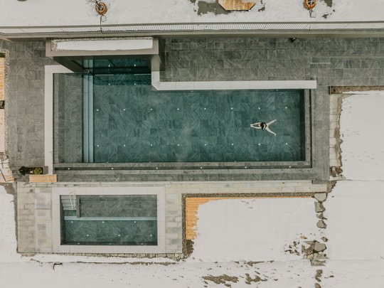 Una giornata di relax Persona che nuota in piscina esterna moderna circondata dalla neve
