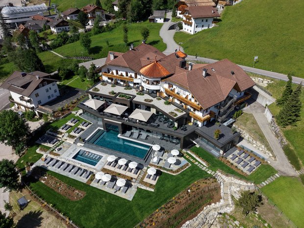 Die vier Häuser unserer Unterkunft im Pustertal Luftaufnahme eines Hotels mit Pool, Sonnenschirmen und Liegestühlen auf grünem Rasen