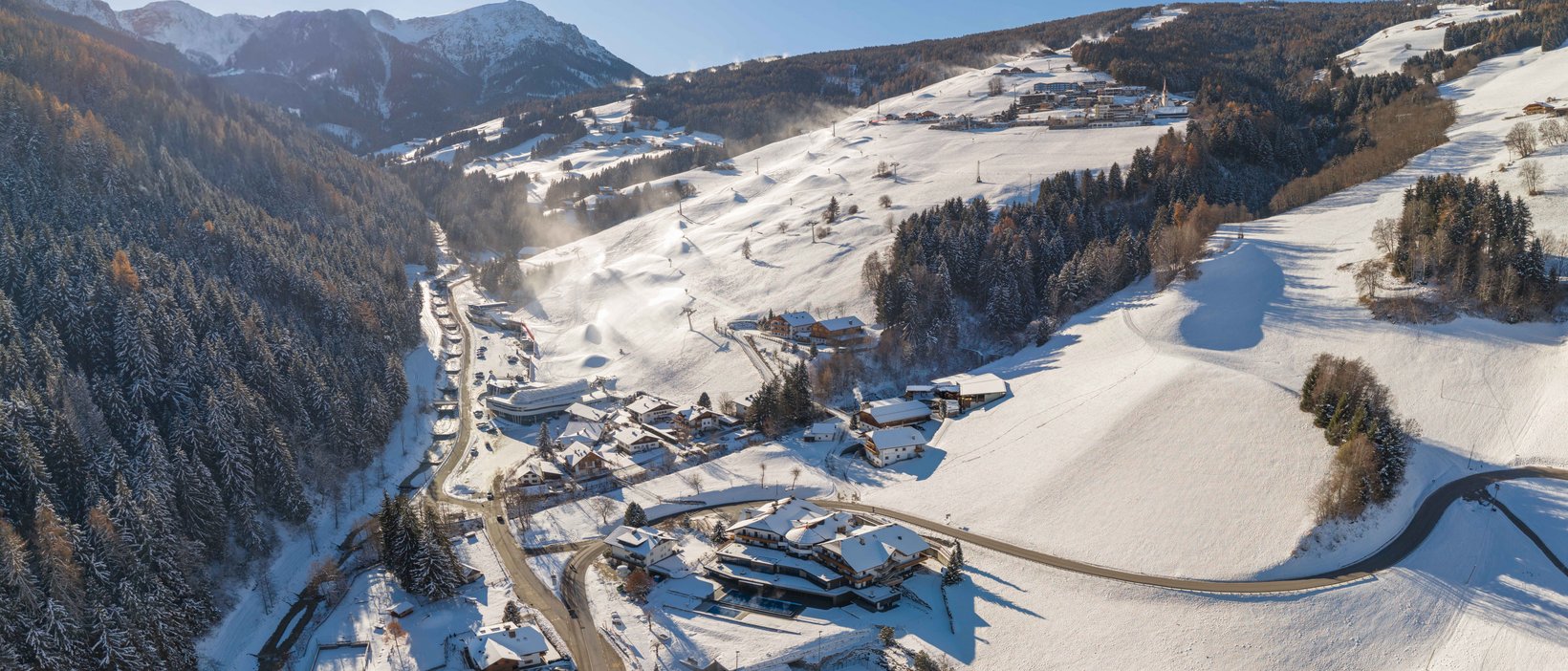 Unforgettable skiing holiday on Plan de Corones/Kronplatz Aerial view of a snowy mountain village under bright sunlight