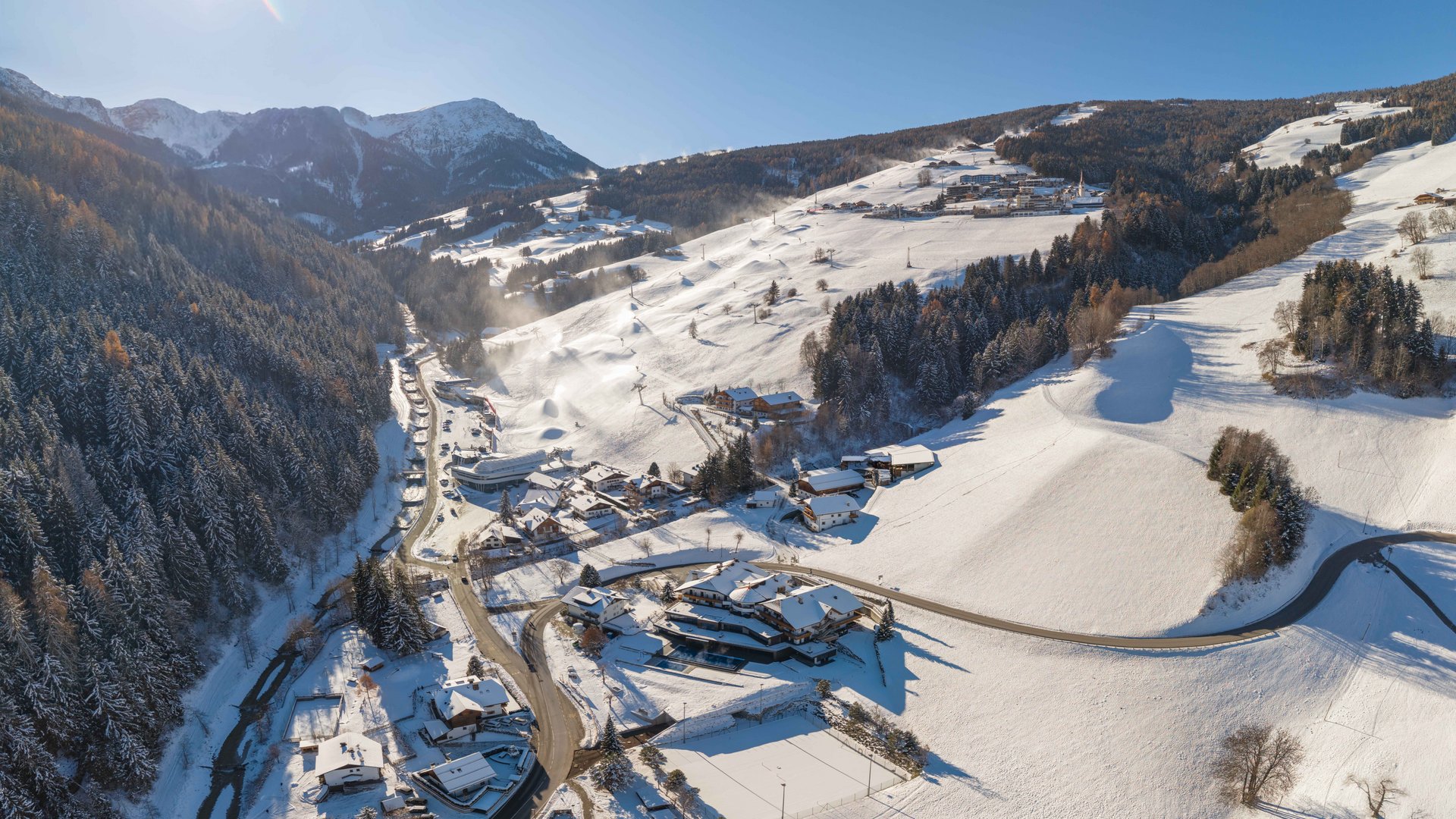 Il nostro hotel sul Plan de Corones: posizione top! Vista aerea di un villaggio di montagna innevato con sole splendente