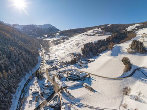 Unforgettable skiing holiday on Plan de Corones/Kronplatz Aerial view of a snowy mountain village under bright sunlight