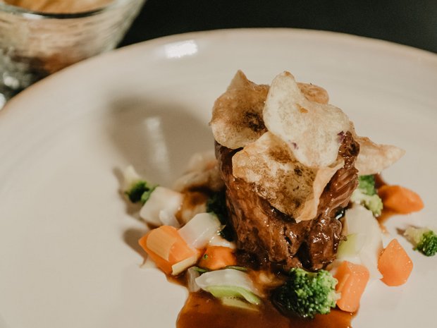 Hotel 4 stelle in Val Pusteria: sostenibile per natura Filetto di manzo su verdure con salsa e chips su piatto bianco