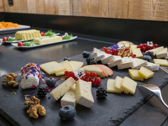 Concedetevi una pausa Varie tipologie di formaggi con bacche e noci su piatto nero