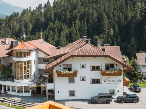 A freer holiday: your holiday apartment in Olang Hotel Christoph in mountain landscape with surrounding forest and parked cars